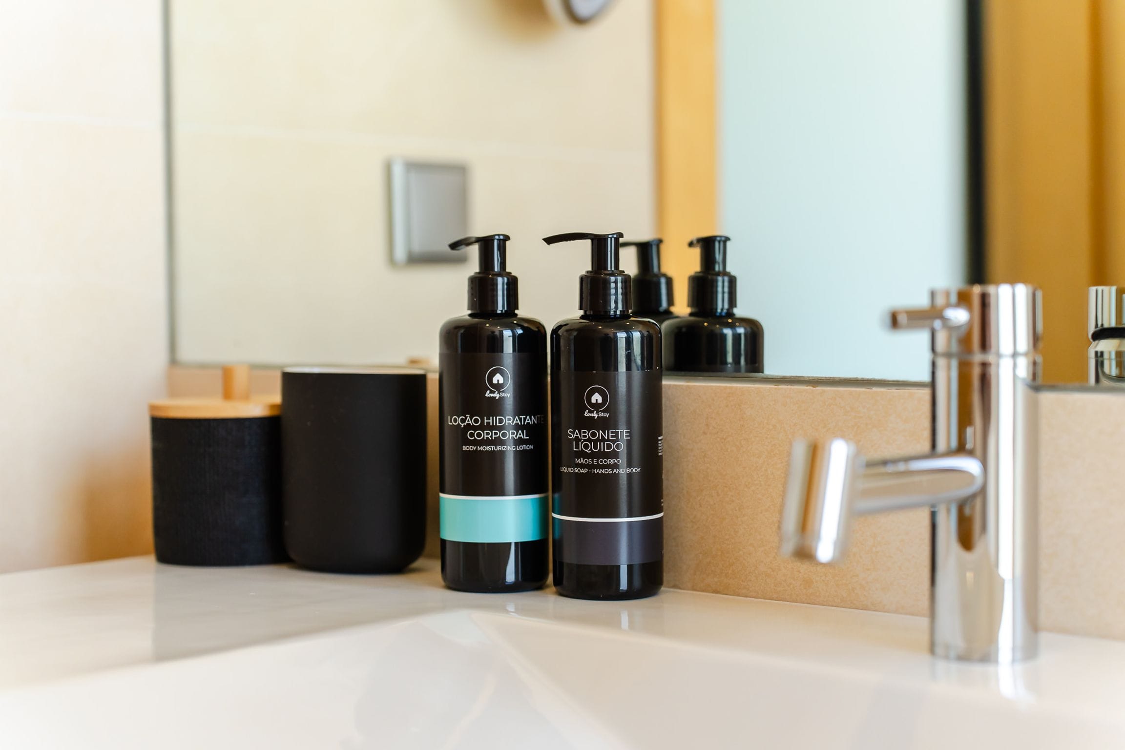 Body lotion and liquid soap bottles beside a chrome tap
