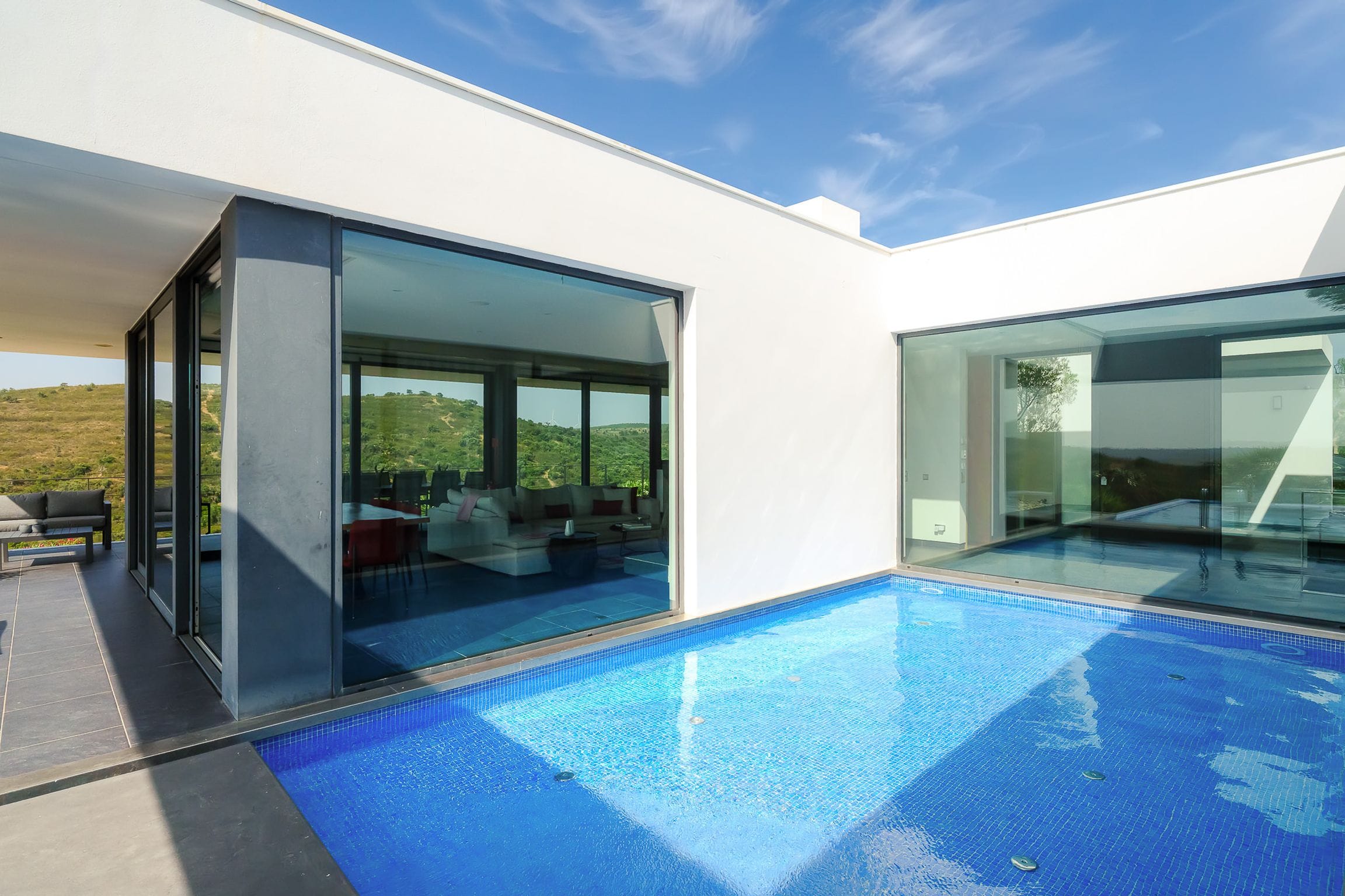 Courtyard section of the pool reflecting the glass walls of the living room, hills visible through the glazing