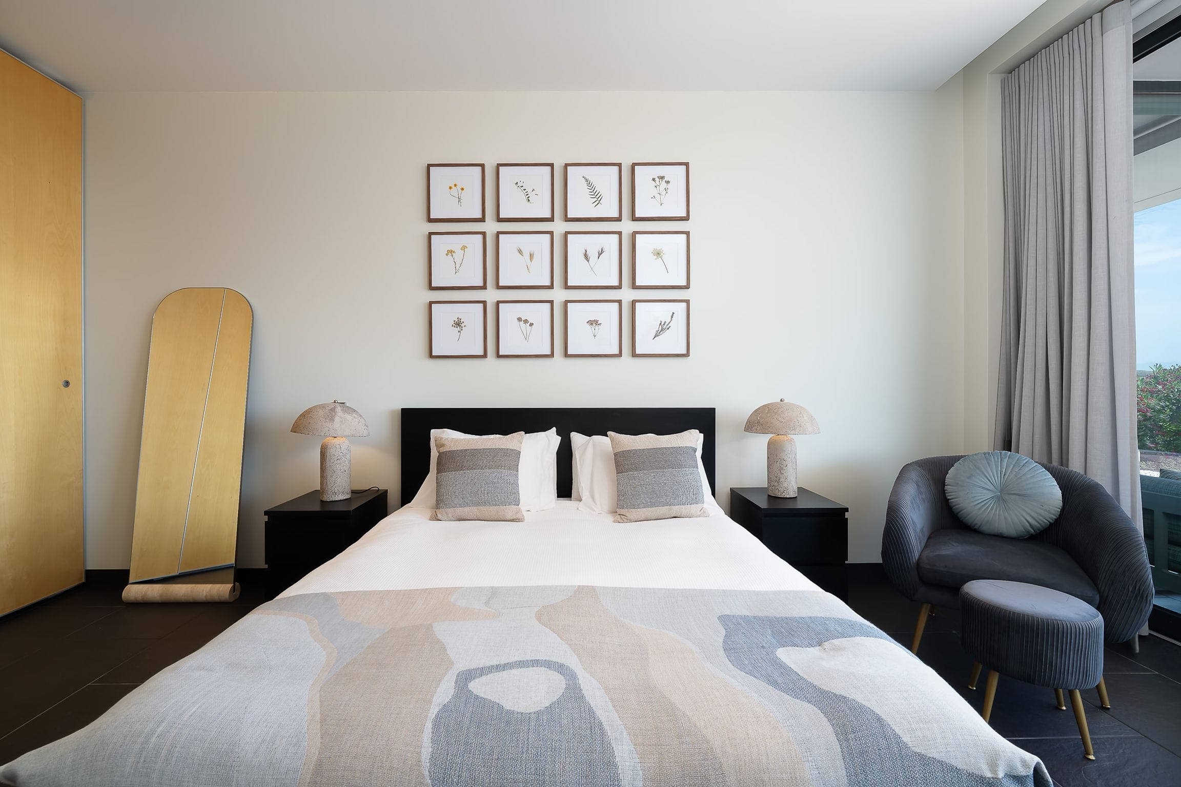 Double bedroom with a grid of pressed-flower prints above the bed and a velvet armchair