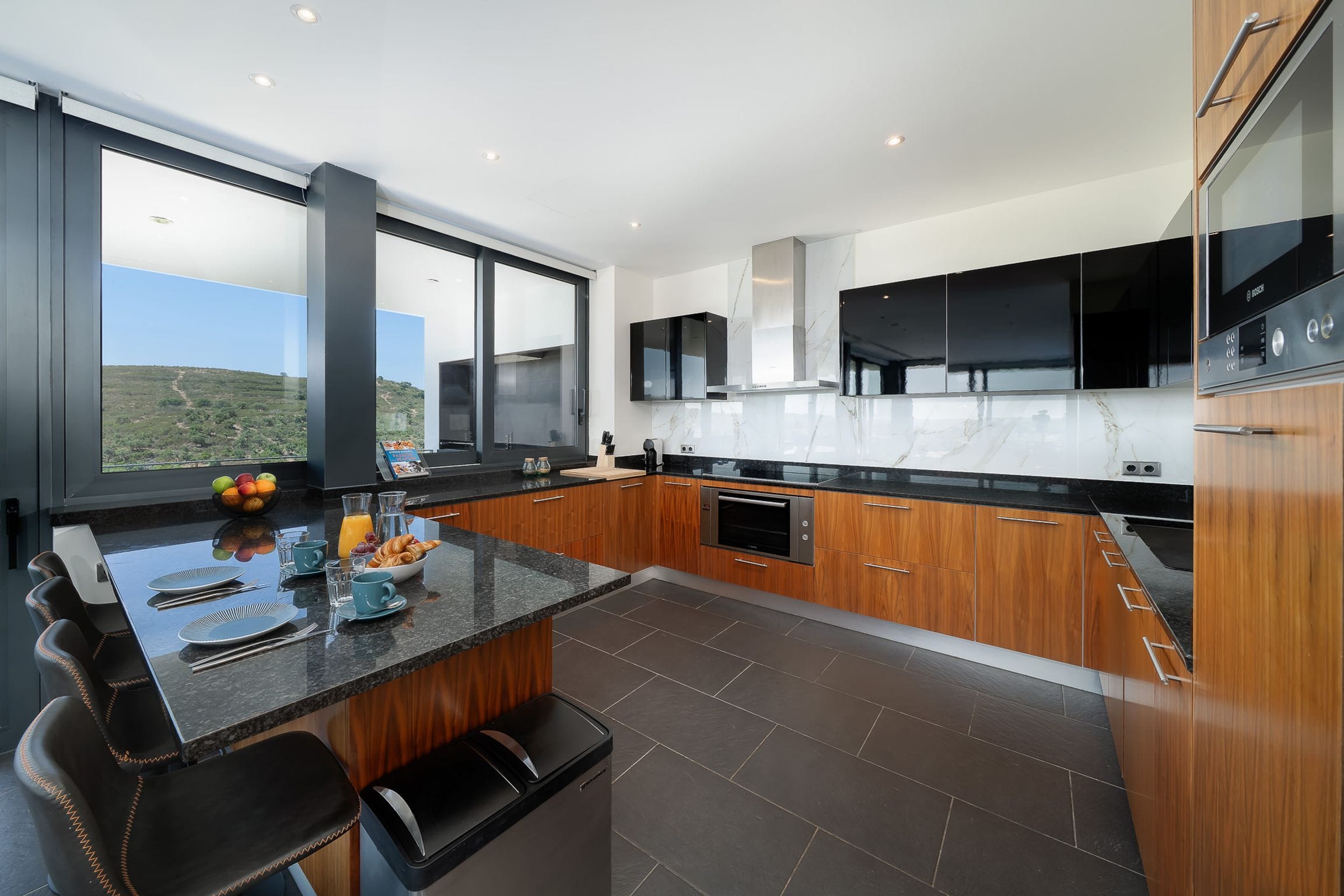 Breakfast laid on a black granite island beside a window facing the hills