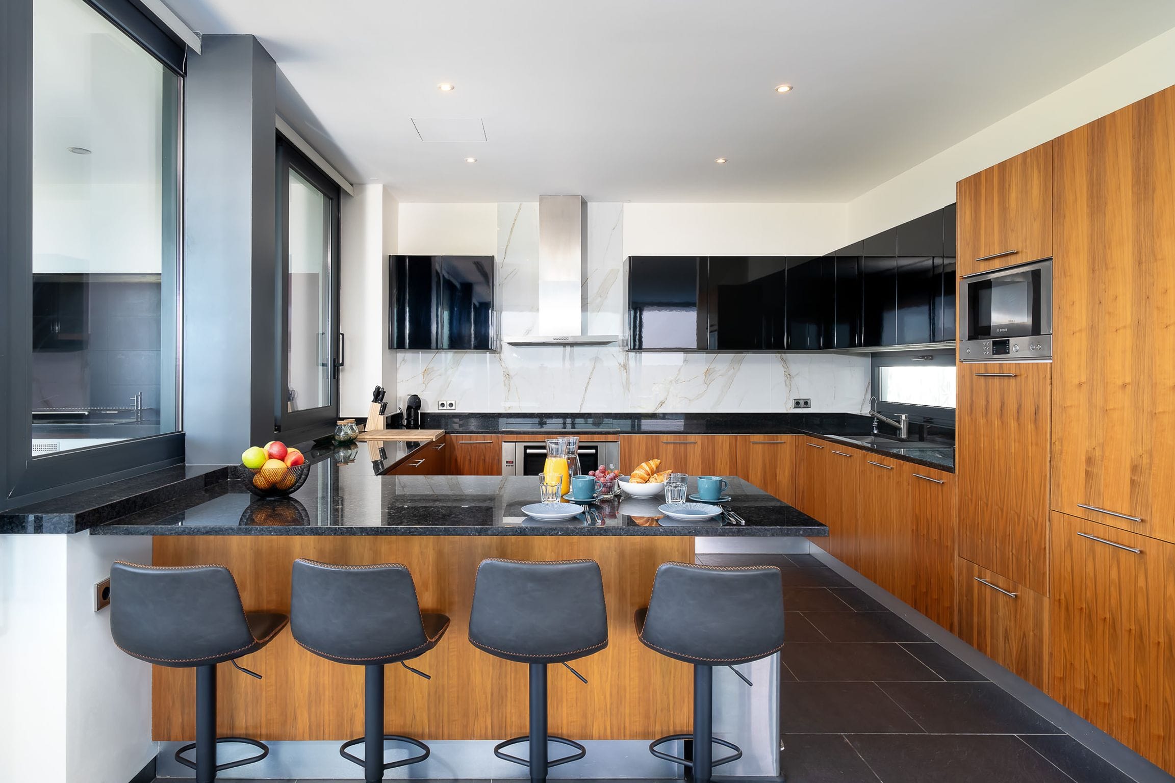 Walnut and black-glass kitchen with a granite breakfast island and four bar stools