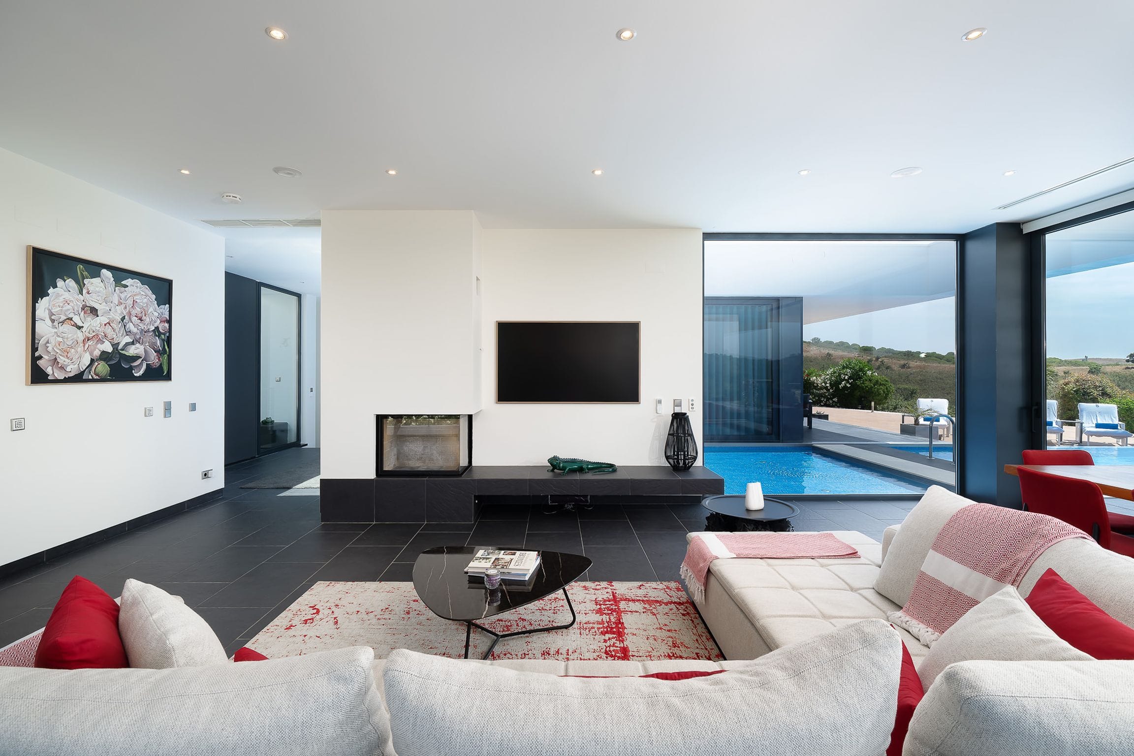 Living room with a white sectional sofa, a double-sided fireplace and a view to the courtyard pool
