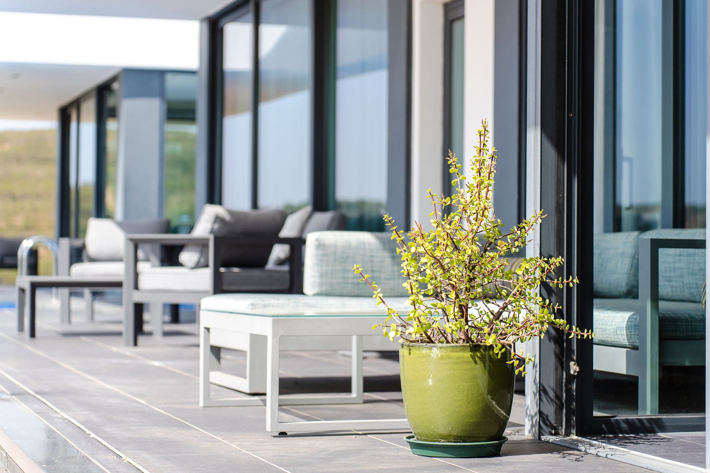 Glazed green planter on the terrace beside outdoor sofas and glass doors